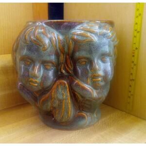 ceramic planter featuring four cherubic or angelic faces.
